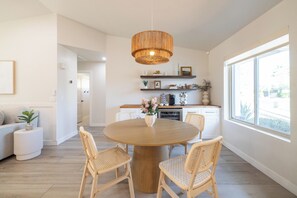 Eine moderne Küche mit einem runden Holztisch, Korbstühlen und einer hängenden Leuchte.