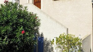 A building with a white stucco exterior, a wooden door, and a pergola. - Beach Holiday Home in Cap D'agde (Agde)