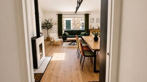 A modern interior with a wooden floor, a dining area with a table and chairs, a sofa, and a fireplace. - Loft Sablais - Plein centre - Parking- Plage (Les Sables-d´Olonne)
