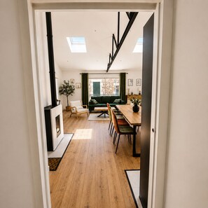 Ein modernes Interieur mit Holzboden, einem Essbereich mit Tisch und Stühlen, einer Couch und einem Kamin.