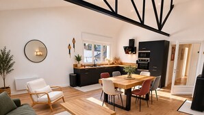 A modern living room with a sofa, a coffee table, and a dining area with chairs and a table. - Loft Sablais - Plein centre - Parking- Plage (Les Sables-d´Olonne)