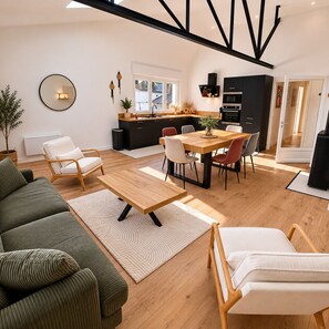 Ein modernes Wohnzimmer mit einer Couch, einem Couchtisch und einem Essbereich mit Stühlen und einem Tisch.