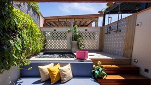 Une terrasse avec un canapé bleu, des marches en bois, une petite fontaine et une pergola.