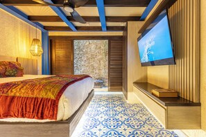 Ein Schlafzimmer mit Bett, Fernseher und Blick ins Freie.