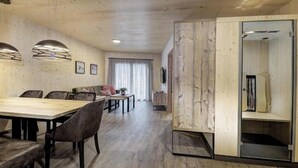 Een modern interieur met een houten eettafel, stoelen, een bank en een schuifdeur die leidt naar een ruimte met de tekst 'PENSION THERM'.