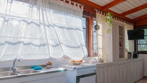 Eine Küche mit Spüle, Herd und einem Fenster mit Vorhängen.
