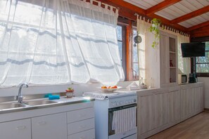 Eine Küche mit Spüle, Herd und einem Fenster mit Vorhängen.