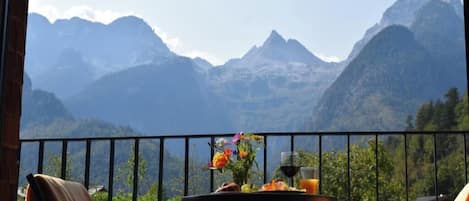 A balcony with a table set for breakfast, overlooking a mountainous landscape.