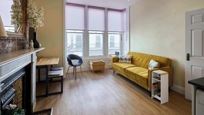 Ein Wohnzimmer mit einer Couch, einem Sessel, einem kleinen Tisch, einem Bücherregal und einem Kamin.