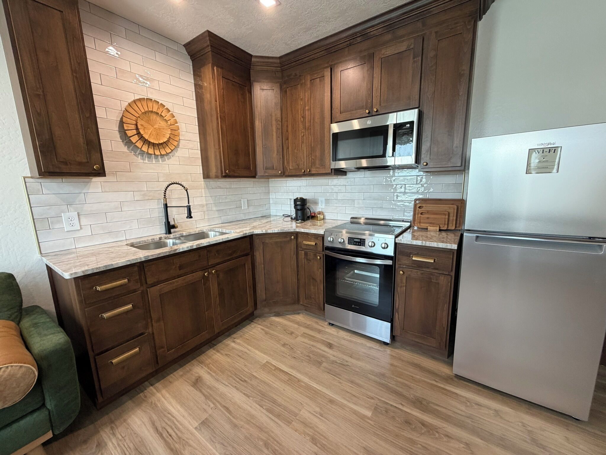 A modern kitchen with wooden cabinets, a stainless steel refrigerator, a built-in oven, and a microwave.