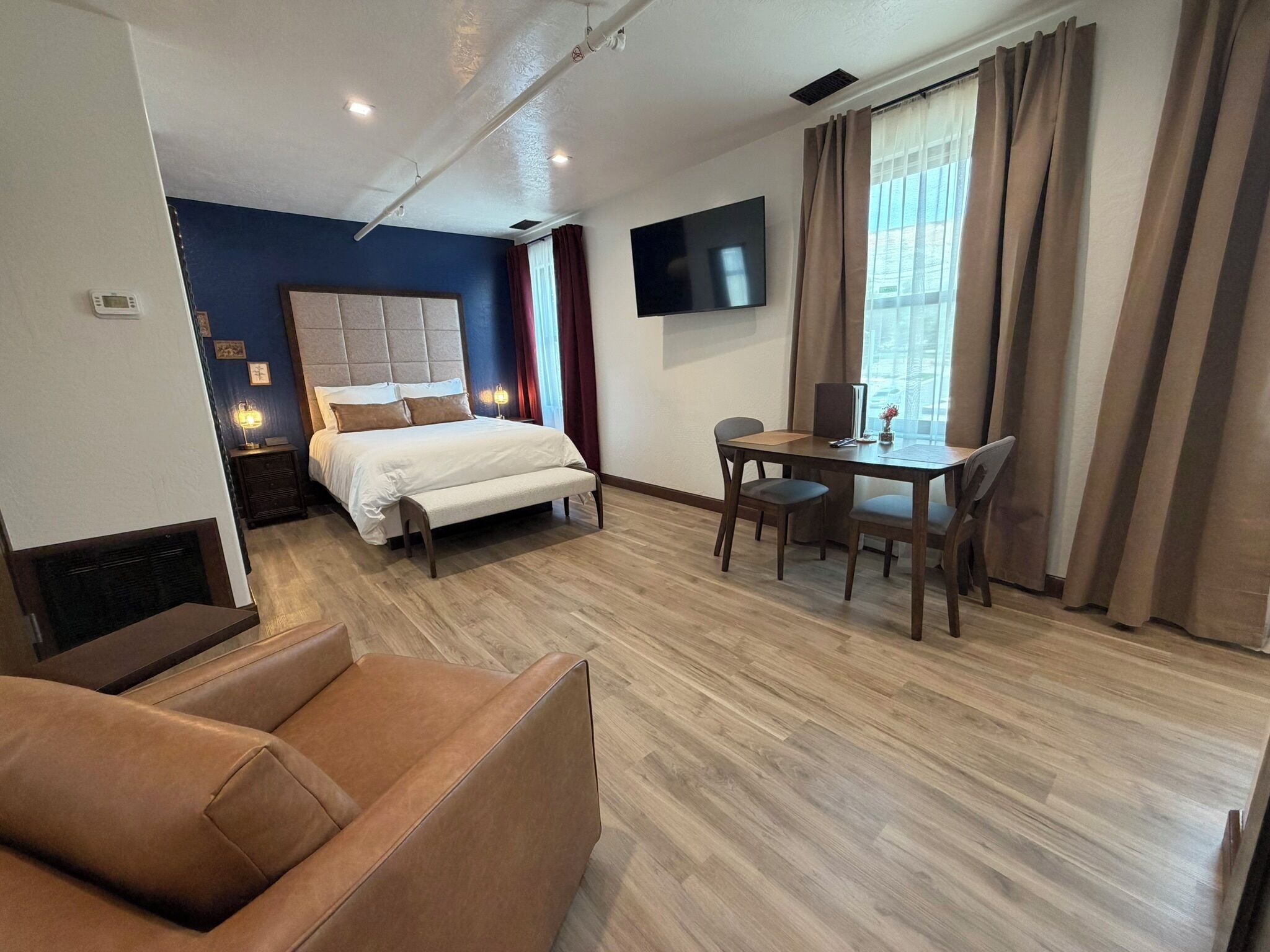 Habitación de hotel con cama, escritorio, silla, sofá y televisor.