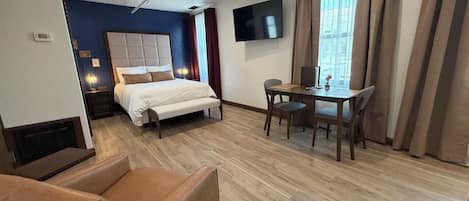 A hotel room with a bed, a desk, a chair, a sofa, and a TV.