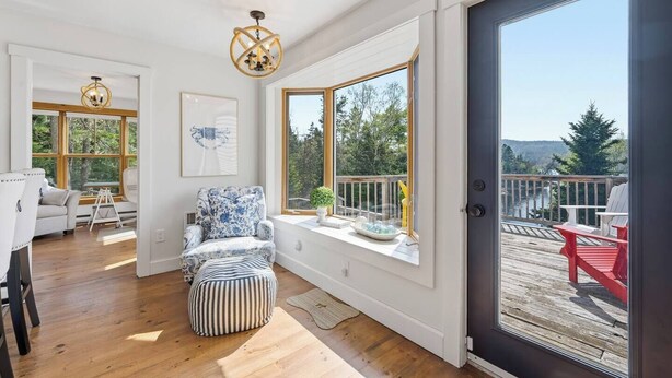 Une pièce dotée d’une grande fenêtre, d’une terrasse en bois, d’une chaise et d’un banc.