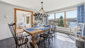 Un espace repas avec une table en bois, des chaises noires et un luminaire suspendu.