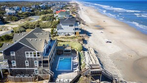A beachfront property with a swimming pool, multiple decks, and a view of the beach and ocean. - Beachfront Oasis w Dune Walkover, Pool n Spa & More! (Corolla)