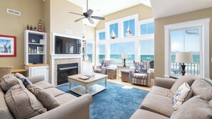 A spacious living room with a fireplace, comfortable seating, a television, and a view of the ocean. - Beachfront Oasis w Dune Walkover, Pool n Spa & More! (Corolla)