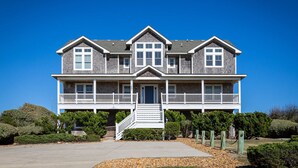 A two-story house with a front porch, a staircase, and a driveway. - Beachfront Oasis w Dune Walkover, Pool n Spa & More! (Corolla)