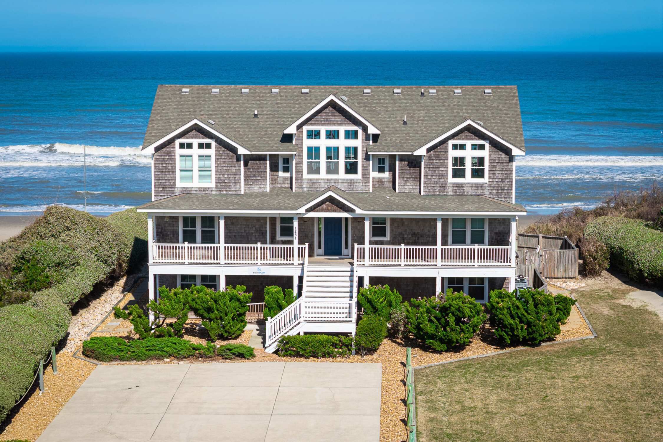 A two-story house with a balcony, a front porch, and a view of the ocean.