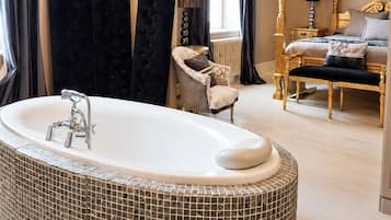 A spacious bathroom with a freestanding bathtub, a vanity with a mirror, and a large window with curtains.