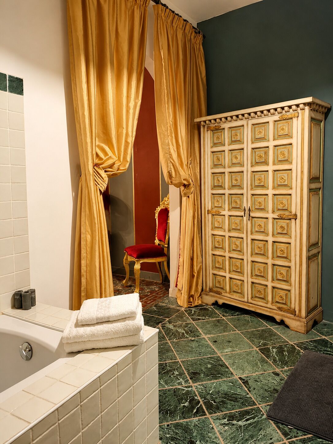 Un baño con una bañera, un tocador con espejo, una silla roja y un mueble de madera grande.