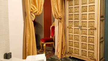 Un baño con una bañera, un tocador con espejo, una silla roja y un mueble de madera grande.