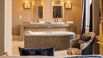 Une salle de bain moderne dotée d’une grande baignoire, de deux vasques et d’un lustre.