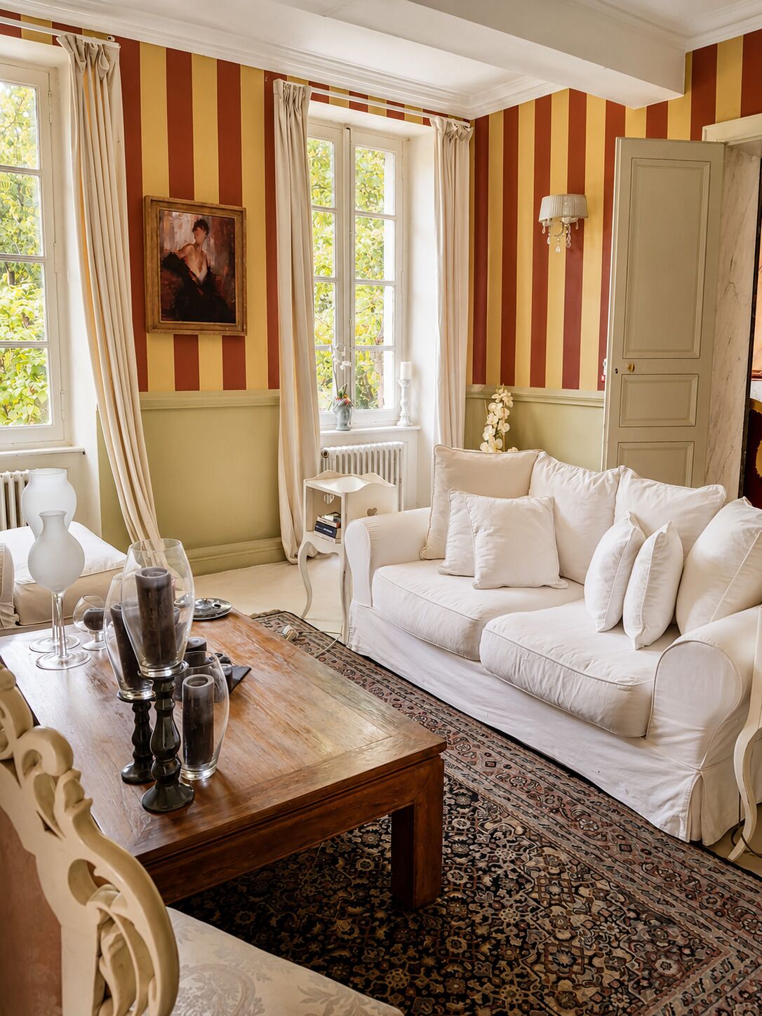 A room with a white sofa, a wooden coffee table, a patterned rug, and striped walls.