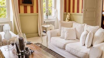 A room with a white sofa, a wooden coffee table, a patterned rug, and striped walls.