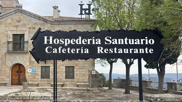 Schild für Hospedería Santuario Cafetería Restaurante vor einem Steinhaus mit einer Holztür und Fenstern.