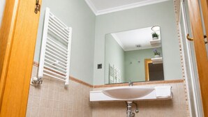 Ein Badezimmer mit einem weißen Waschbecken, einem Spiegel und einem Handtuchhalter.