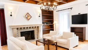 Ein Wohnzimmer mit Kamin, weißen Sofas, einem Couchtisch und einer Deckenleuchte.