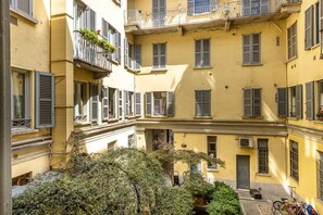 A multi-story yellow building with balconies, shutters, and a courtyard with greenery. - Brera luxury apartment (Milano)