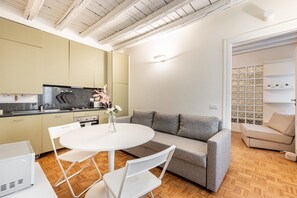Eine moderne Küche mit Esstisch und Stühlen, ein graues Sofa und eine weiße Wand mit einer Zierleiste.