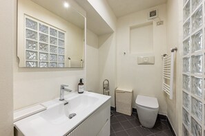A bathroom with a white sink, a mirror, a toilet, and a towel rack. - Brera luxury apartment (Milano)