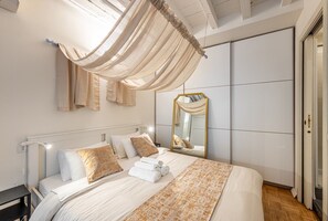Ein Schlafzimmer mit Bett, Nachttisch, Spiegel und Kleiderschrank.