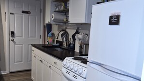 A kitchen with white cabinets, a stove, a refrigerator, and a microwave.