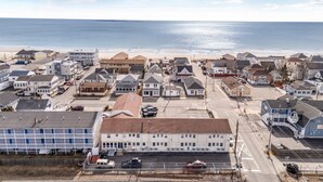 A coastal town with residential buildings, a beach, and a road leading to the sea.