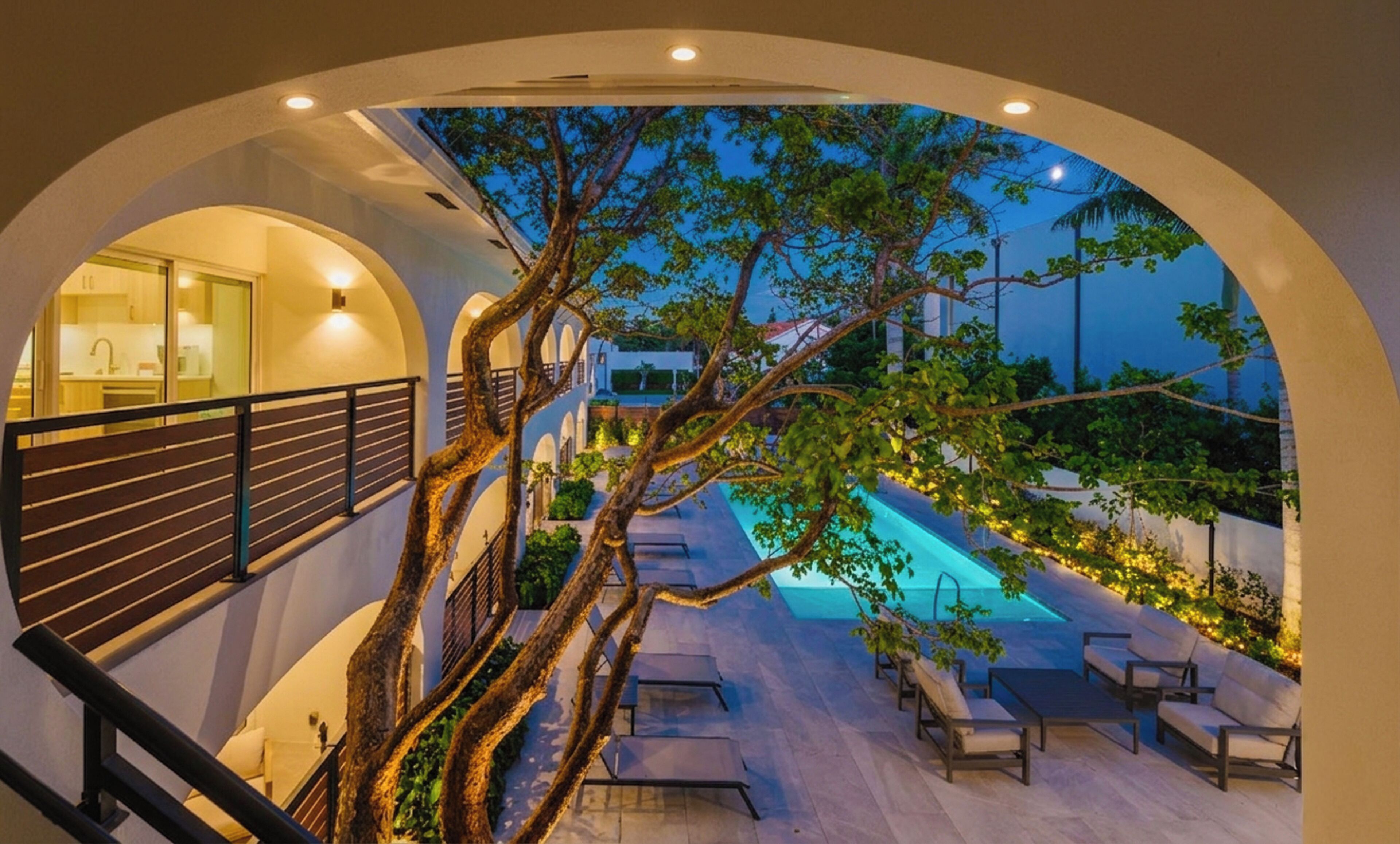 A modern building with a pool, outdoor seating, and a tree in the center.