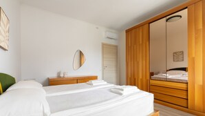A bedroom with a bed, wooden wardrobe, a mirror, and a wall-mounted air conditioner. - Sogno del Garda by Wonderful Italy (Desenzano del Garda)