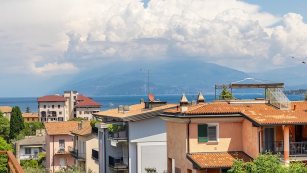 A coastal residential area with buildings, a clear sky, and a distant mountain. - Sogno del Garda by Wonderful Italy (Desenzano del Garda)