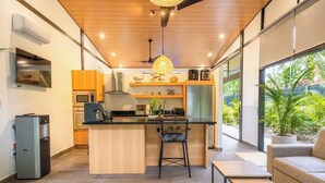 Une cuisine moderne dotée d’un îlot central, d’appareils électroménagers intégrés et d’une grande fenêtre donnant sur un paysage verdoyant.
