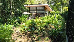 Ein modernes Haus mit Glasfassade, umgeben von üppiger Vegetation.