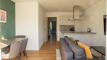 A modern living room with a dining table, sofa, and kitchen area.