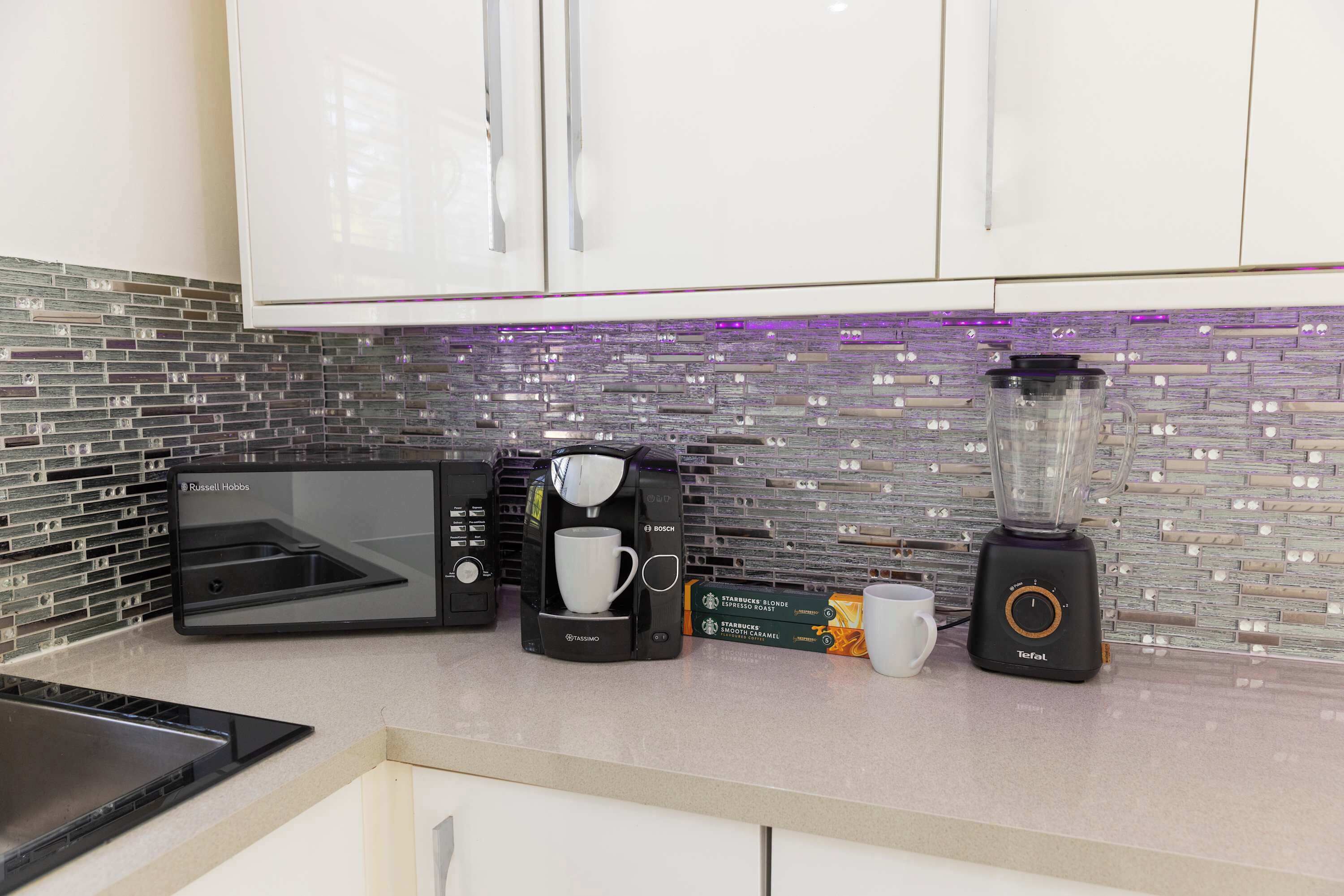 A kitchen with a coffee maker, a blender, and a toaster.