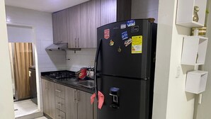 A kitchen with a black refrigerator, wooden cabinets, a gas stove, and a sink. - Centrally located apartment, close to airport, beaches and historical center. (Cartagena de Indias)