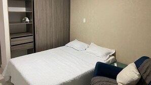 A bedroom with a bed, a wardrobe, and an air conditioning unit. - Centrally located apartment, close to airport, beaches and historical center. (Cartagena de Indias)