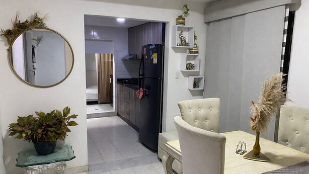 A modern kitchen with a refrigerator, cabinets, and a dining area with a table and chairs. - Centrally located apartment, close to airport, beaches and historical center. (Cartagena de Indias)