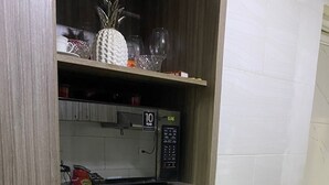 A kitchen with a microwave, a 10-year warranty sign, and a shelf with kitchenware. - Centrally located apartment, close to airport, beaches and historical center. (Cartagena de Indias)