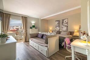 Une chambre d’hôtel compacte comprenant un lit, un canapé, un bureau et une vue sur la ville.