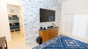 Ein modernes Schlafzimmer mit Fernseher, Holzschrank und gemustertem Teppich.